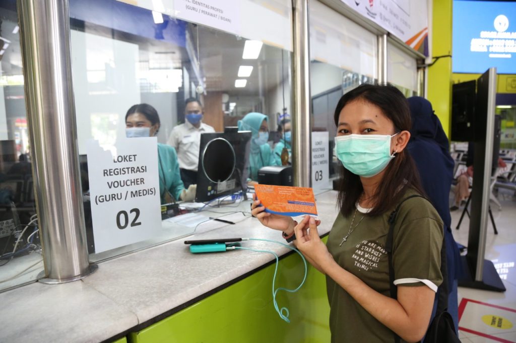 Seorang gurutenaga kesehatan usai mengambil voucher tiket gratis di Stasiun Gambir